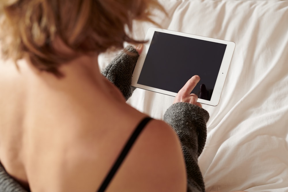 woman in black brassiere holding white ipad