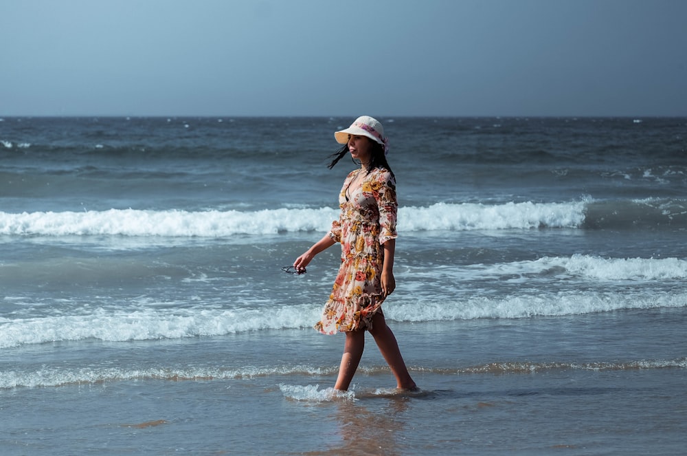 woman in brown and white floral dress standing on beach during daytime