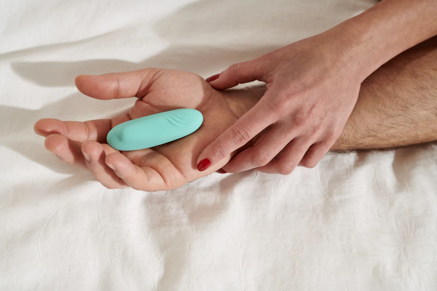 Two hands sharing a small mint-green massager