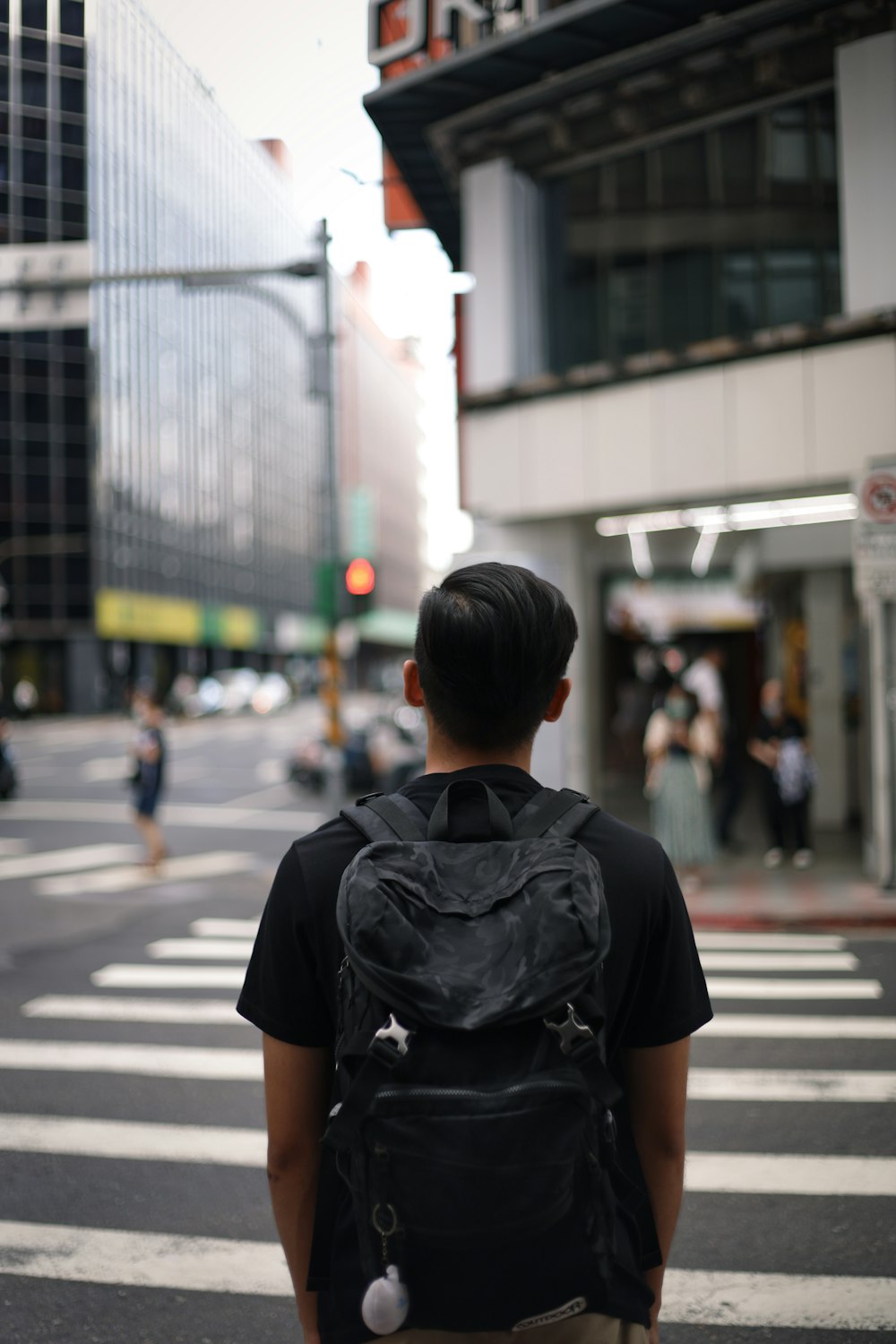 homem de camiseta preta andando na faixa de pedestres durante o dia