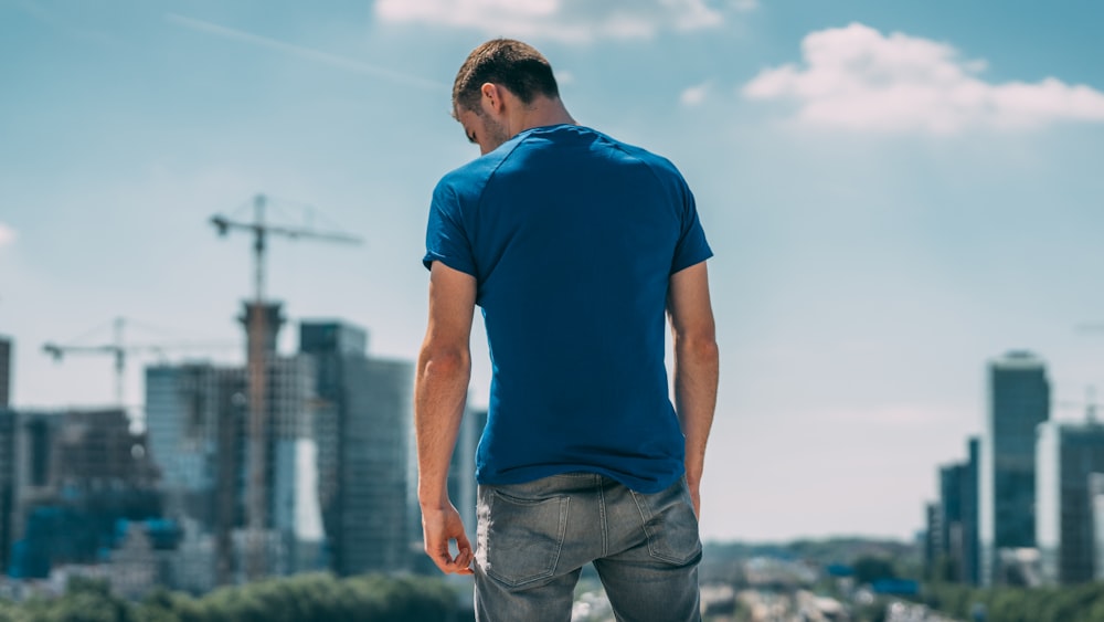 man in blue crew neck t-shirt and gray denim jeans standing on green grass field