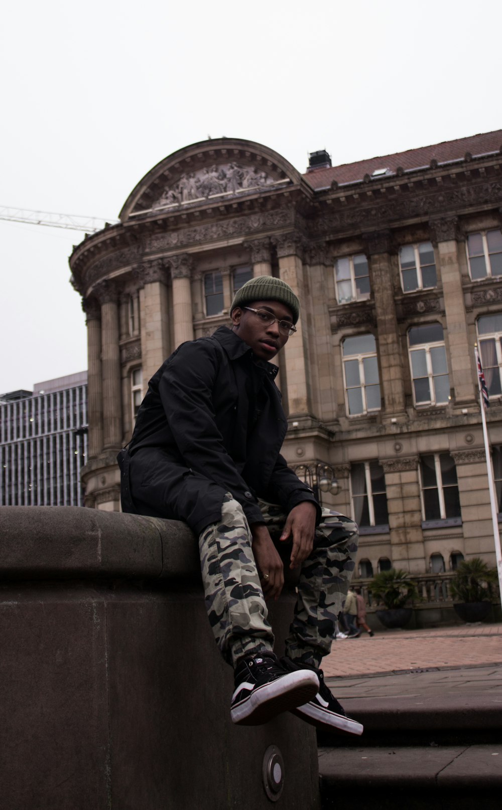 man in black jacket sitting on concrete bench