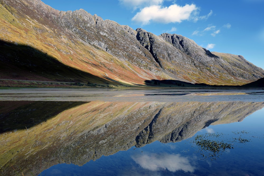 body of water near mountain during daytime