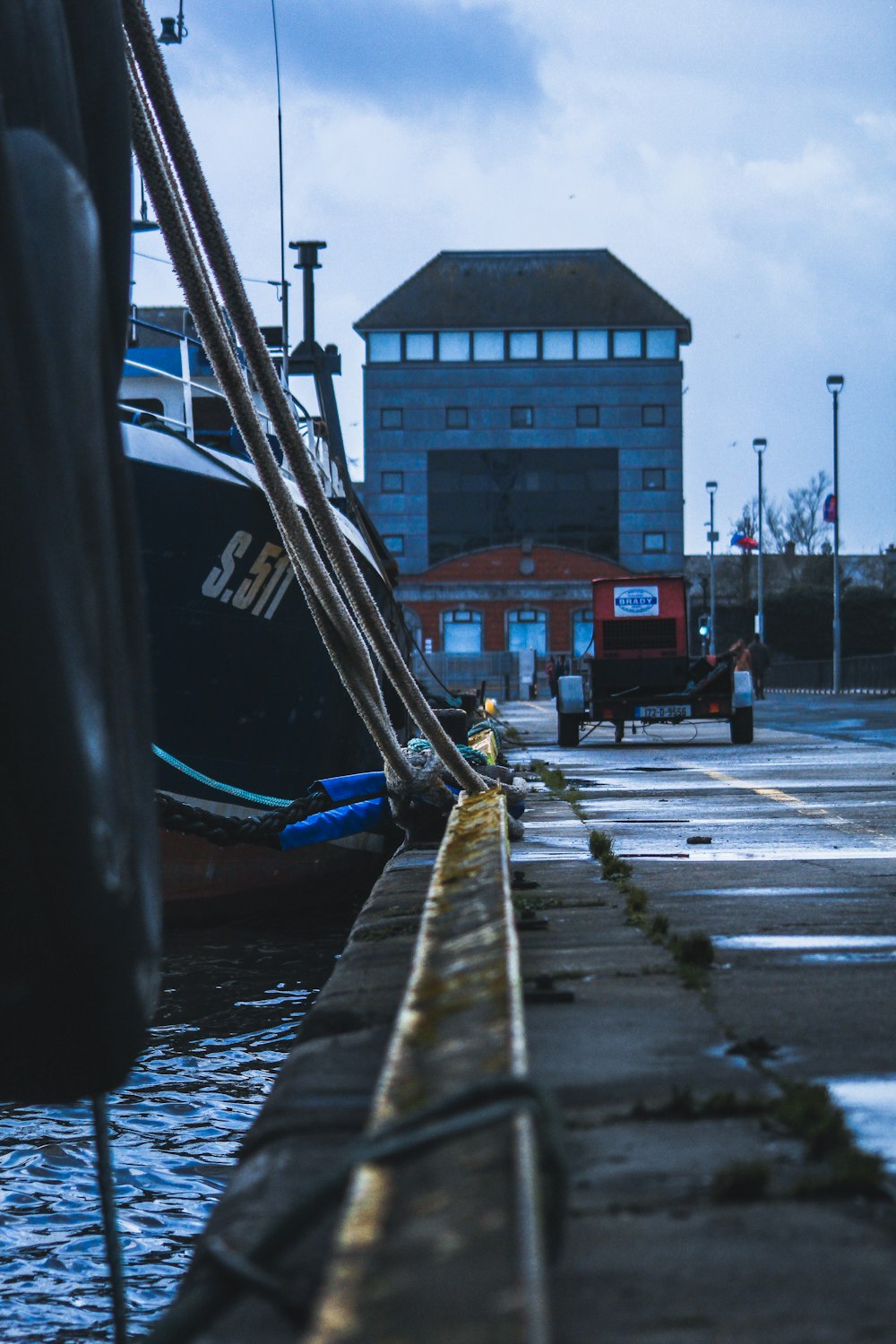 blue boat on dock near brown building during daytime