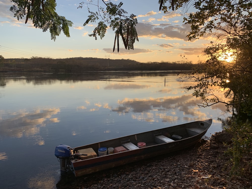 white and red boat on lake during sunset