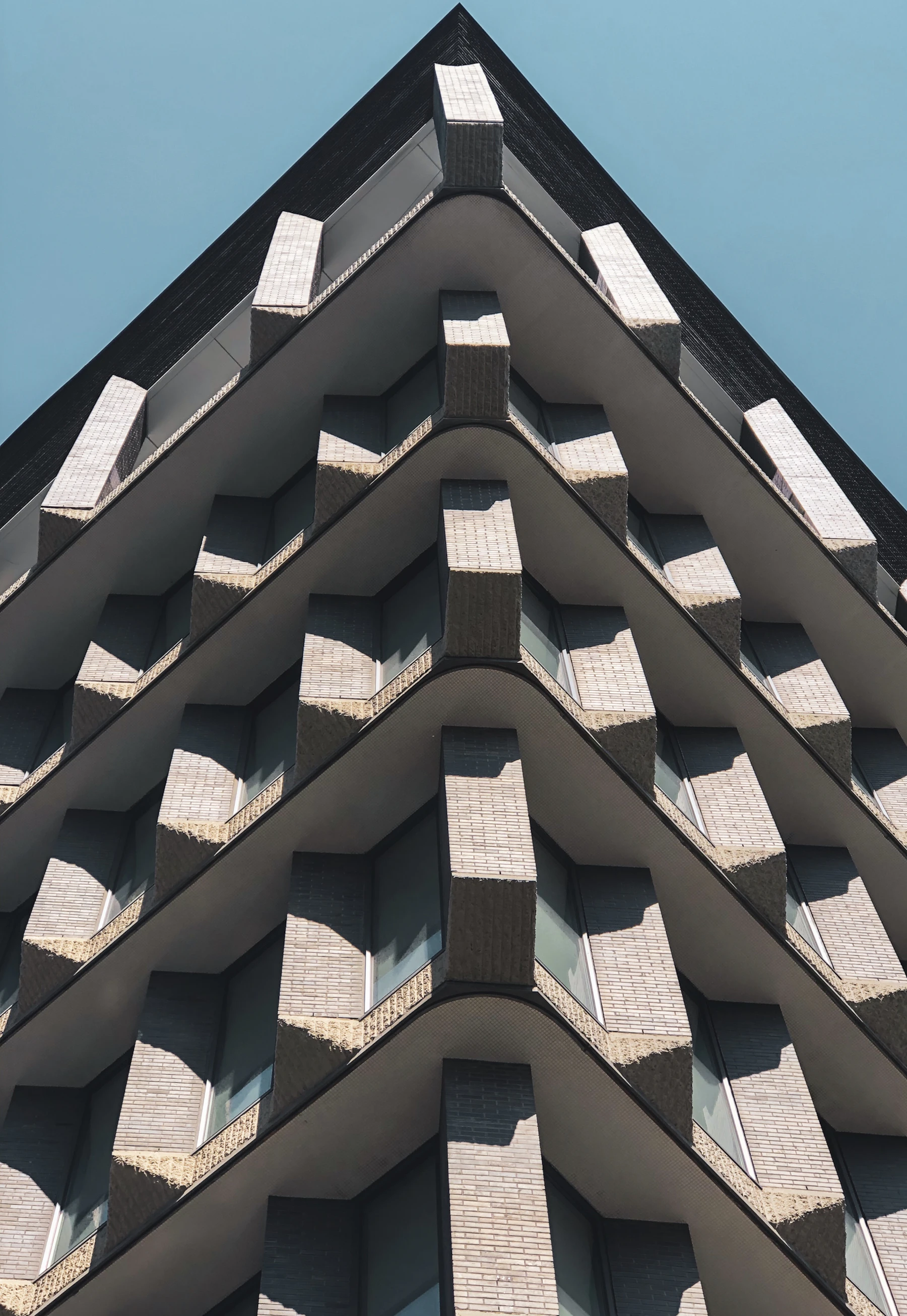 A modernist facade of stacked angular window bays against a clear sky