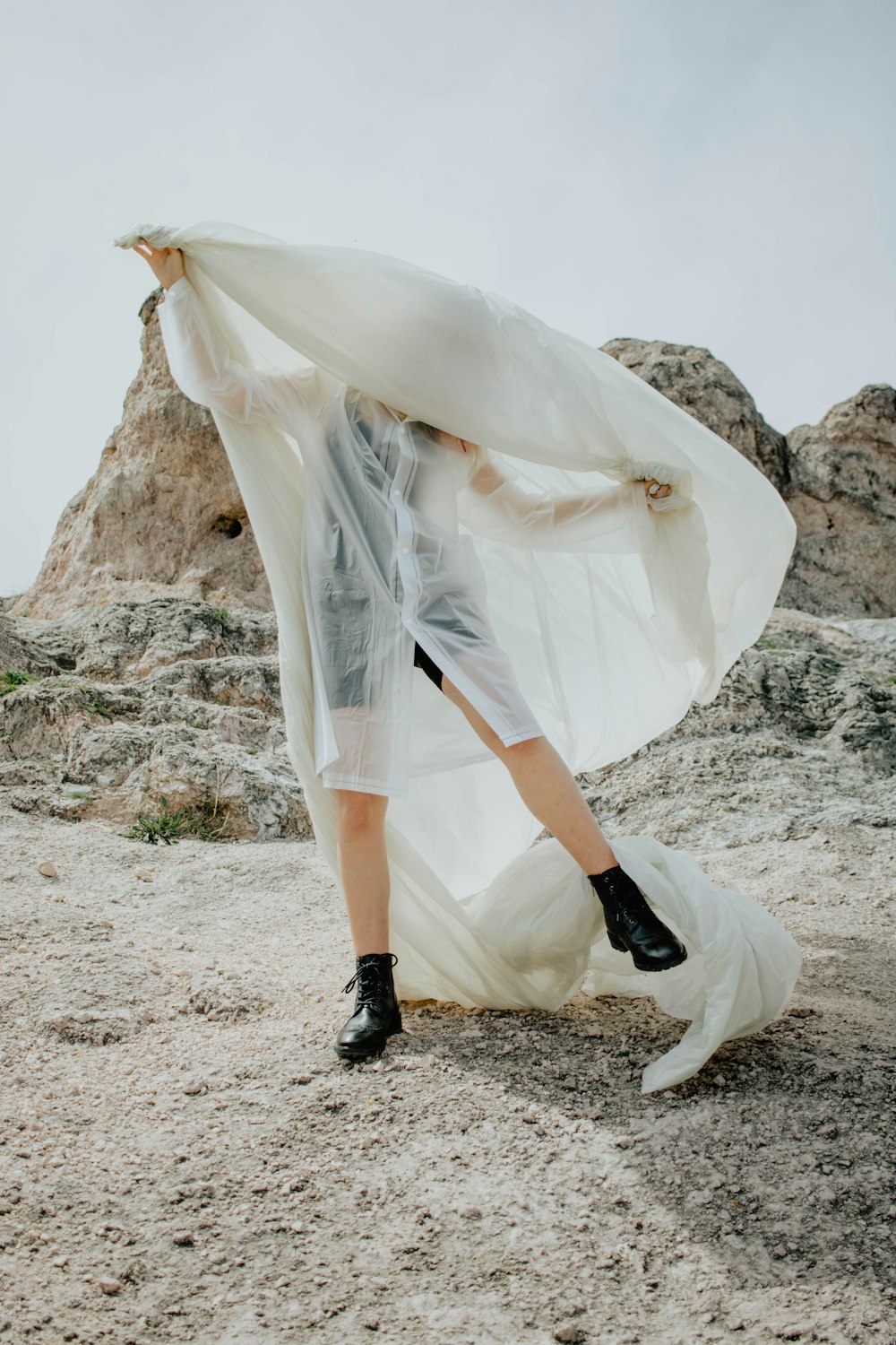 woman in white wedding dress and black boots standing on rocky ground during daytime