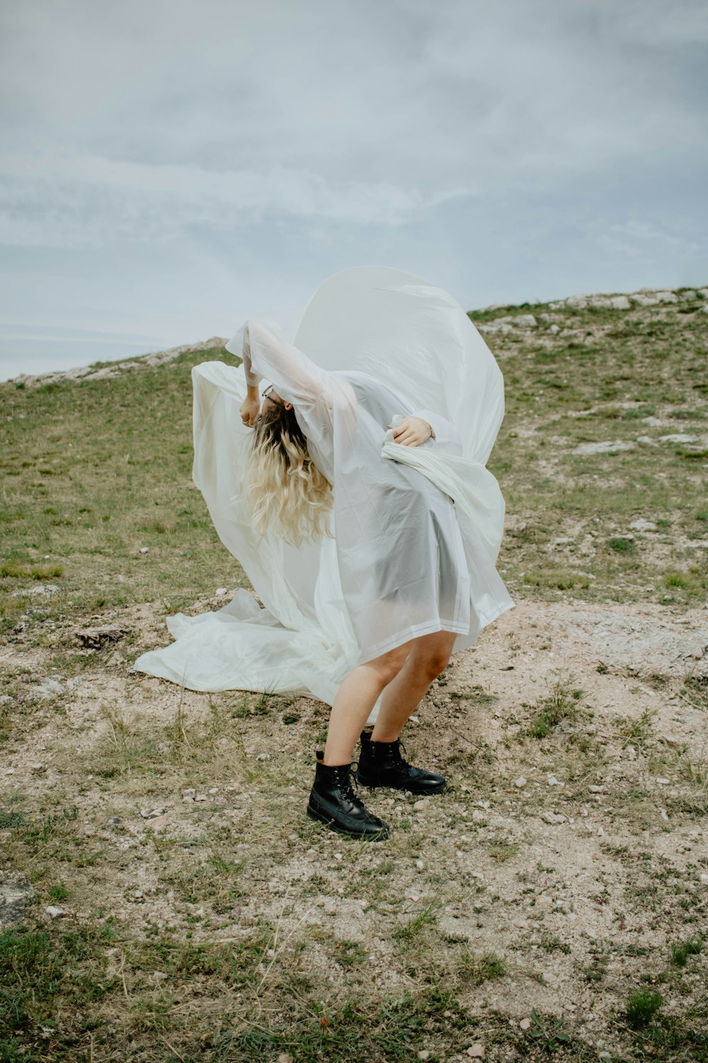 woman in white dress and black leather boots standing on brown field during daytime