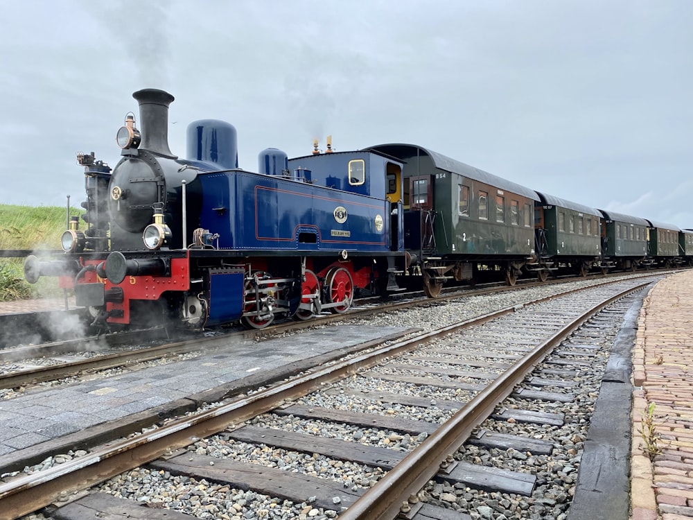 blue and red train on rail tracks under cloudy sky during daytime