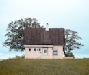 white and black concrete house near green trees under white sky during daytime