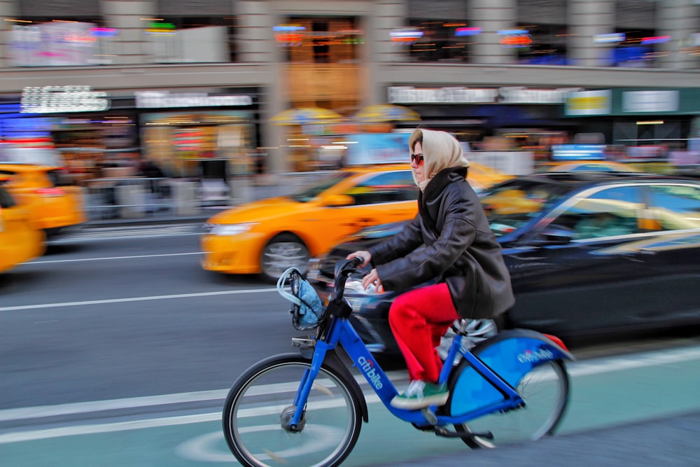 woman in black jacket riding blue motorcycle on road during daytime