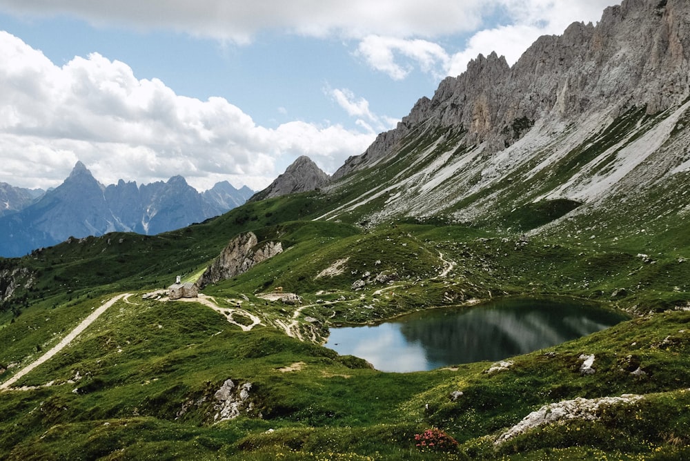 green and brown mountains near lake under white clouds and blue sky during daytime