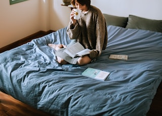 woman in gray sweater sitting on bed