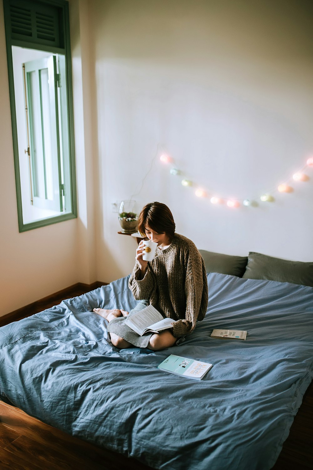 woman in gray sweater sitting on bed