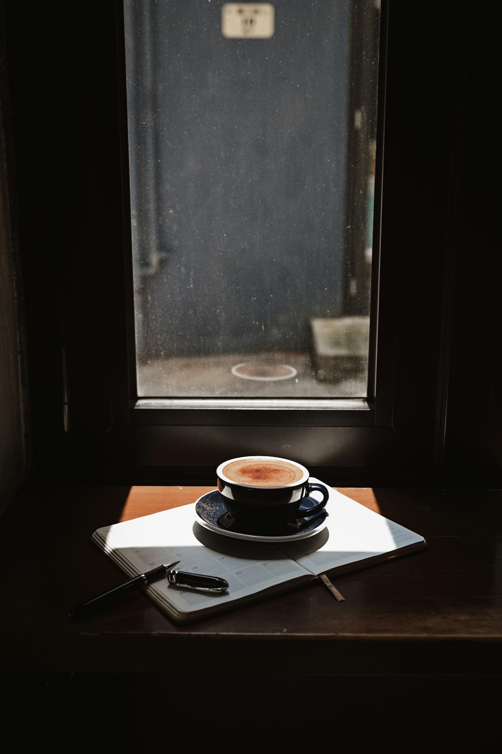 taza de té de cerámica blanca y negra en platillo sobre mesa de madera marrón