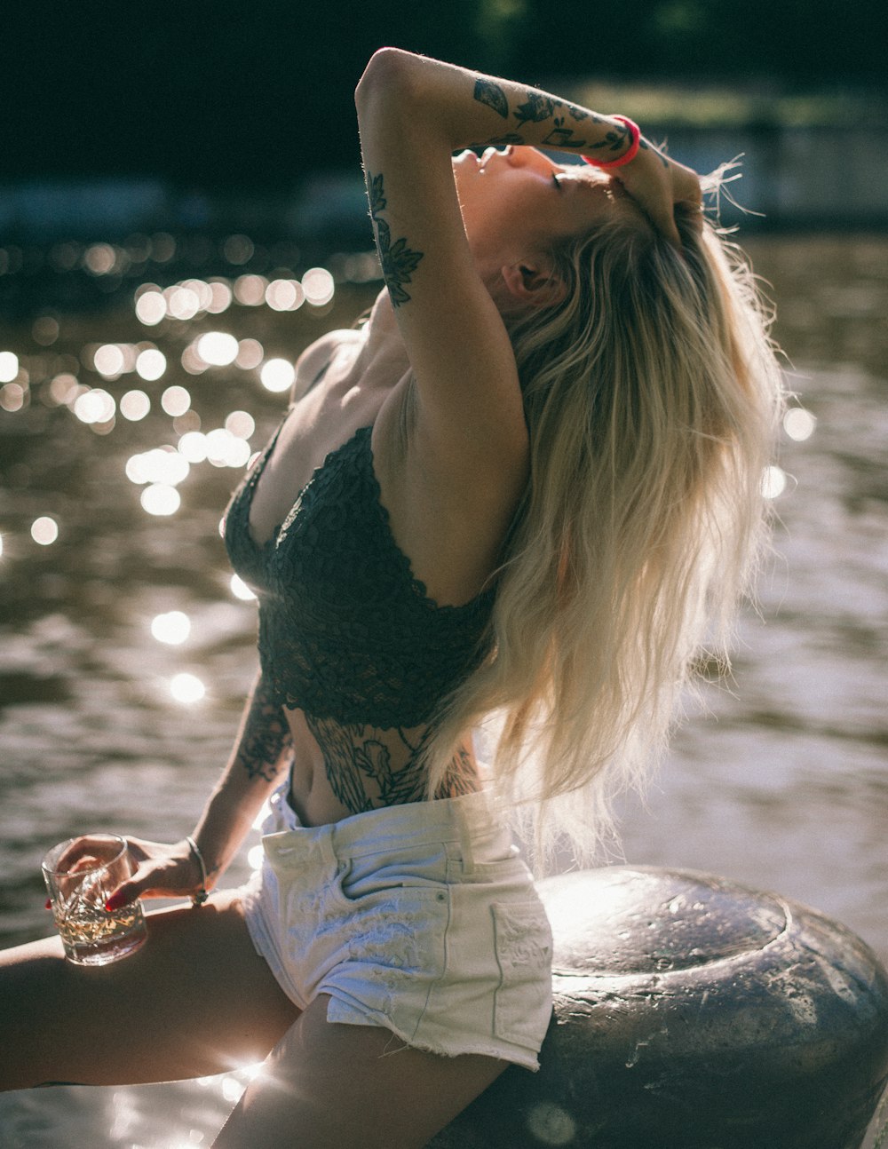 woman in black tank top and white shorts sitting on rock during daytime