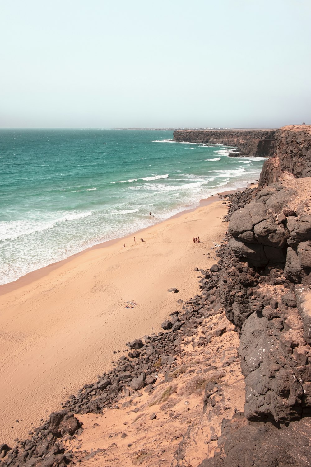 Playa de arena marrón con arena marrón y agua de mar azul durante el día