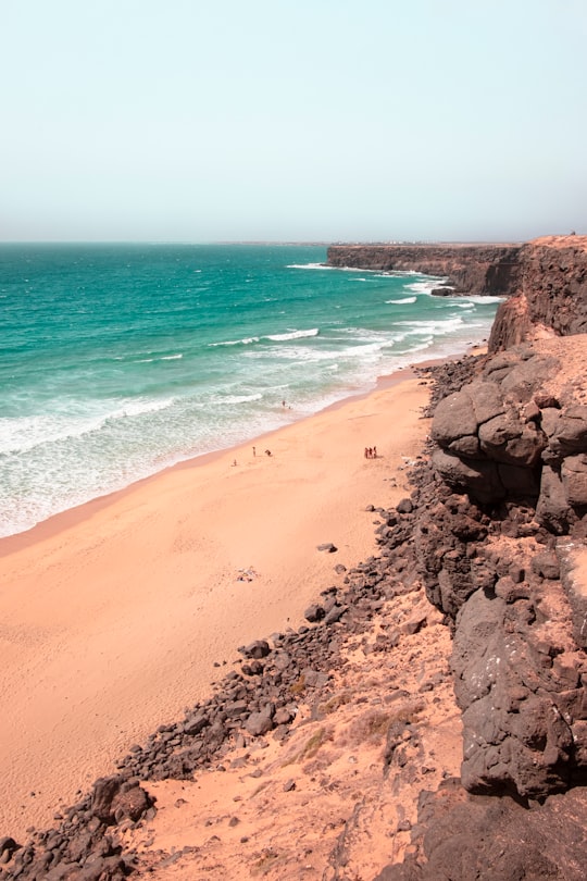 brown sand beach with brown sand and blue sea water during daytime in Fuerteventura Spain