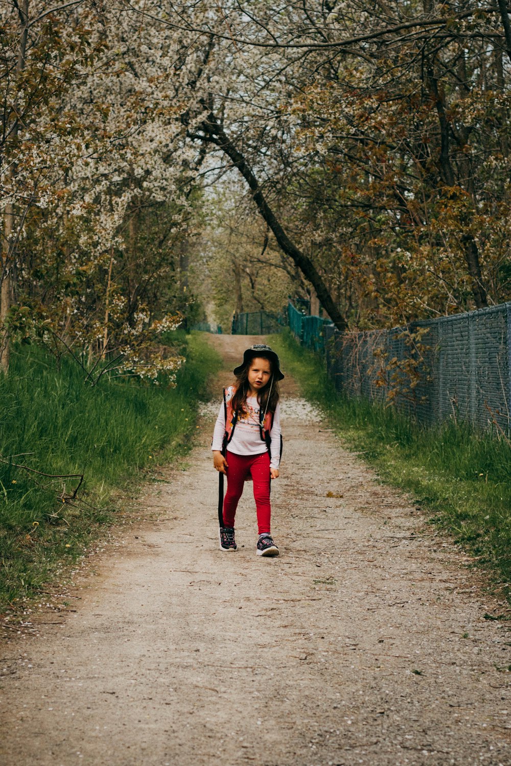 a young girl walking down a dirt road