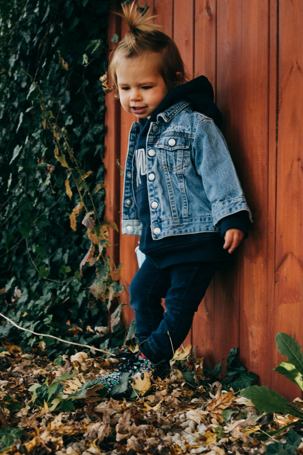 Un bambino piccolo appoggiato a una staccionata di legno