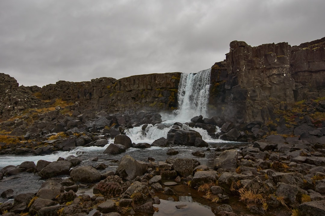 rocky mountain with waterfalls under cloudy sky during daytime