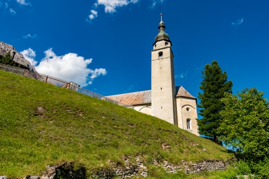 white concrete building on green grass field under blue sky during daytime in Splügen Switzerland