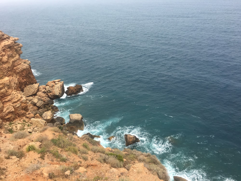 brown rocky shore with blue sea water during daytime