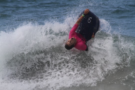 man in red and black shirt and black pants surfing on sea waves during daytime in Isla de Margarita Venezuela