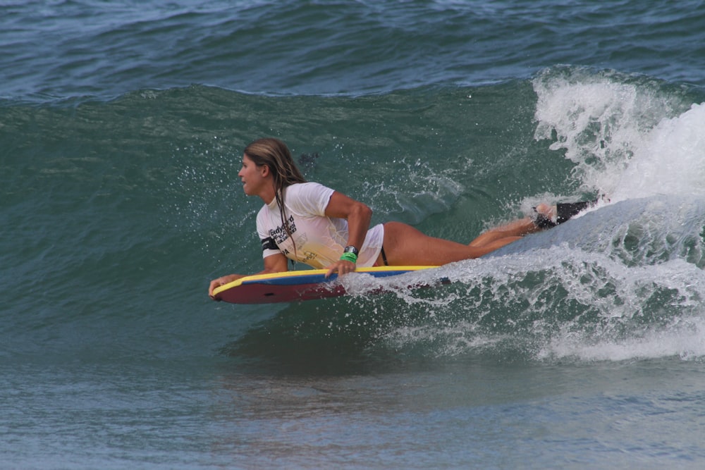 woman in pink and green bikini surfing on sea waves during daytime