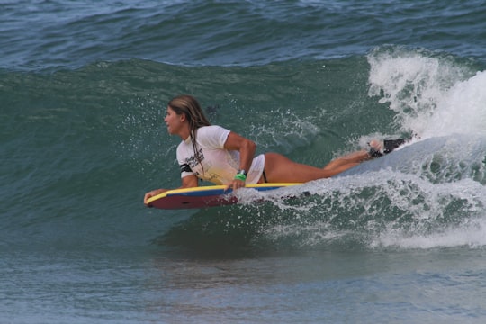 woman in pink and green bikini surfing on sea waves during daytime in Isla de Margarita Venezuela