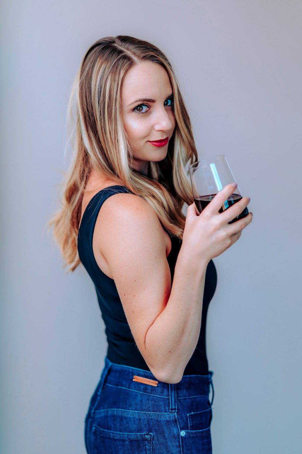 woman in blue tank top holding white ceramic mug