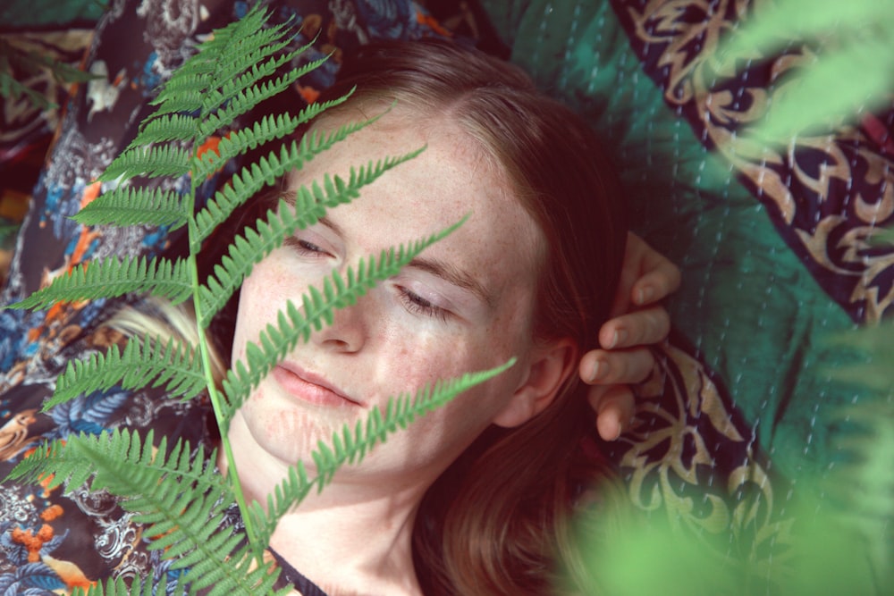 woman in white shirt lying on green leaves
