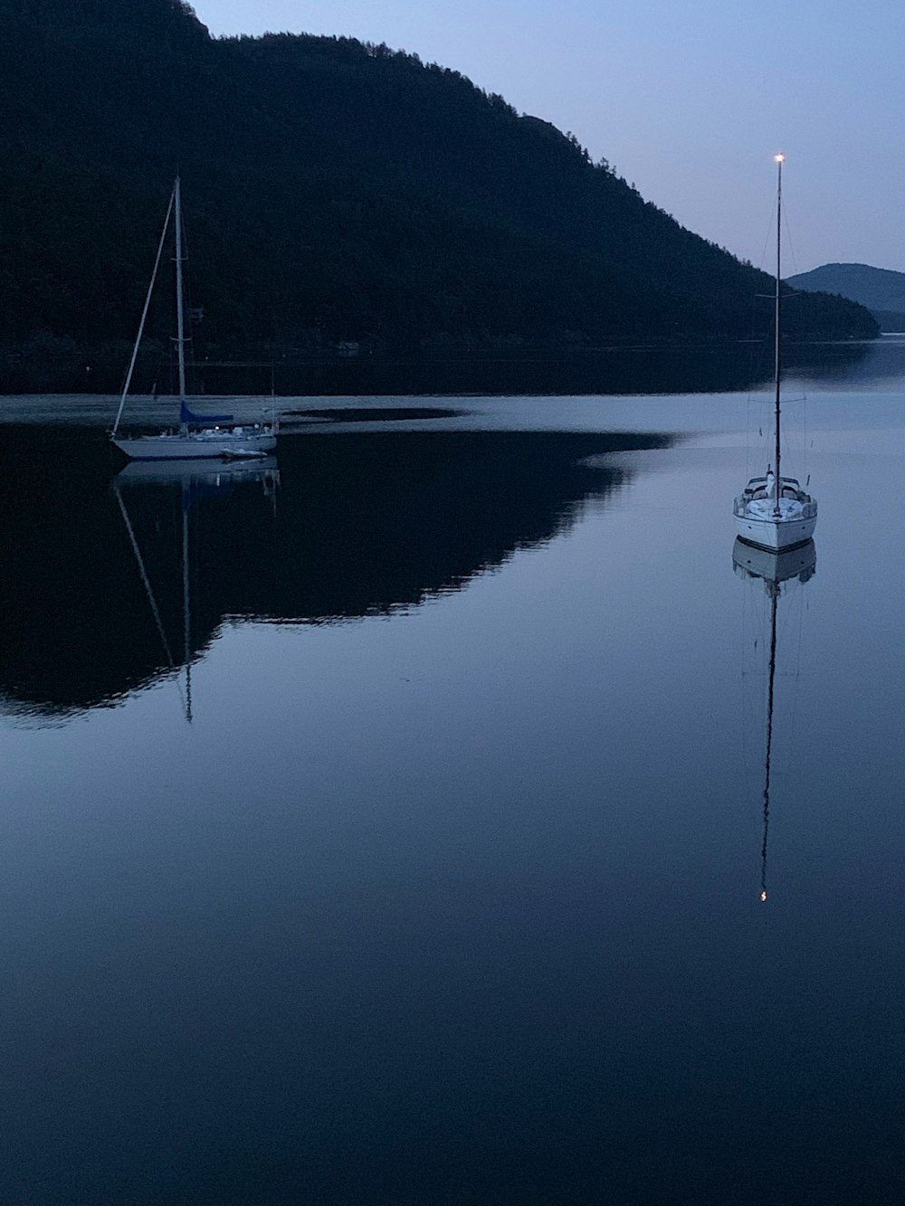 Bateau blanc sur l’eau calme près de la montagne pendant la journée