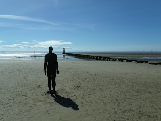 man in black jacket walking on beach during daytime in Crosby Beach United Kingdom
