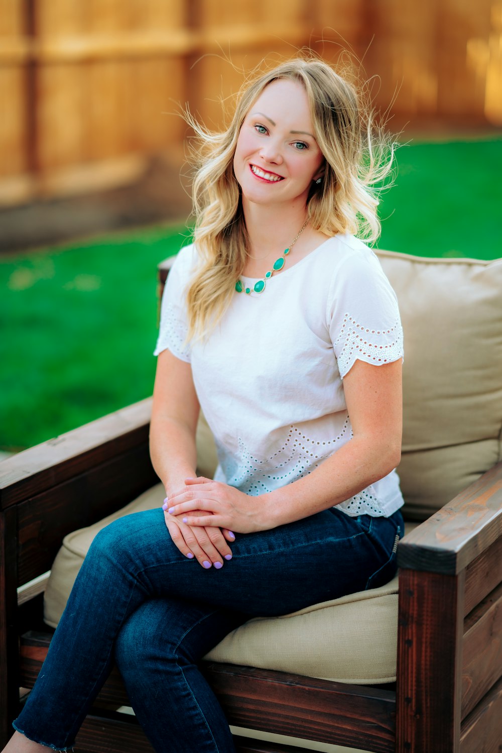 woman in white shirt and blue denim jeans sitting on brown wooden bench