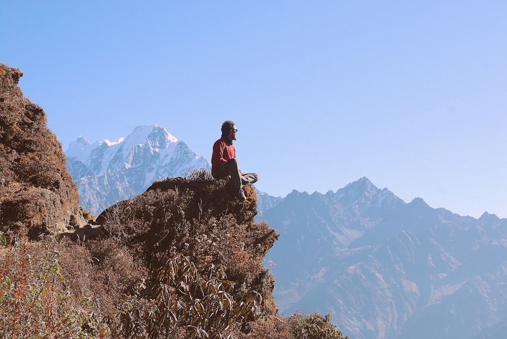 man in black jacket sitting on rock mountain during daytime