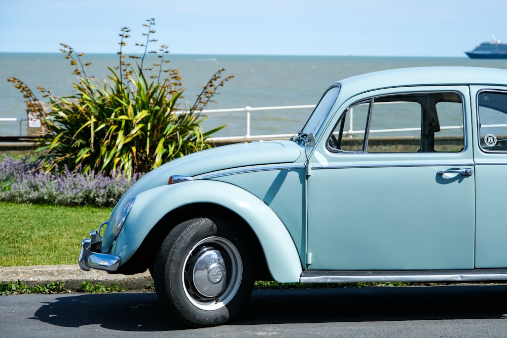 blue and white vintage car on gray asphalt road during daytime