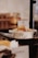 A small bowl filled with pão de queijo, a Brazilian cheese bread, is placed on a black serving stand. The background is softly blurred, highlighting the bowl and its contents. A sign next to the bowl clearly labels the item.