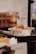 A small bowl filled with pão de queijo, a Brazilian cheese bread, is placed on a black serving stand. The background is softly blurred, highlighting the bowl and its contents. A sign next to the bowl clearly labels the item.