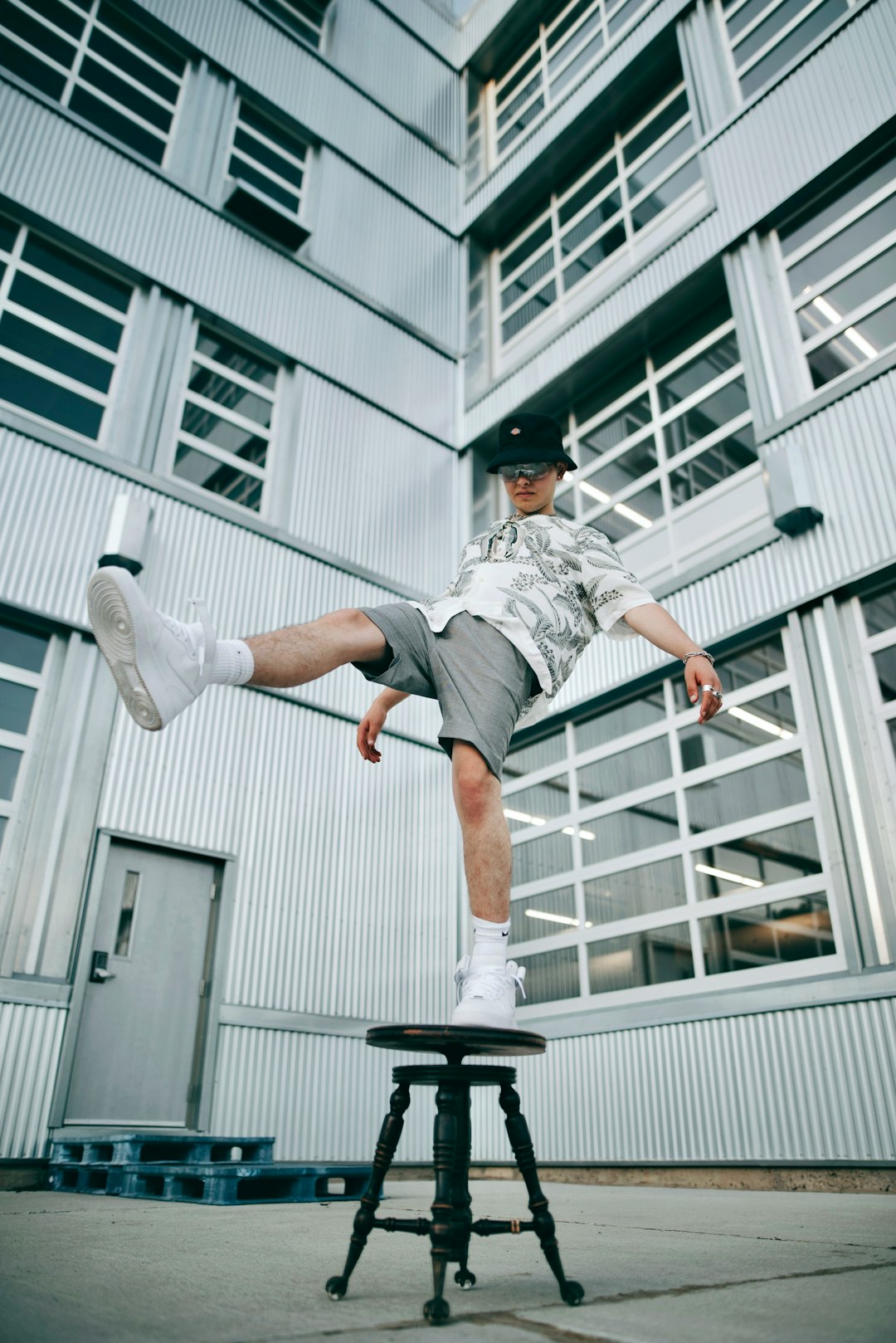 man in grey shirt and grey shorts jumping on grey metal ladder during daytime