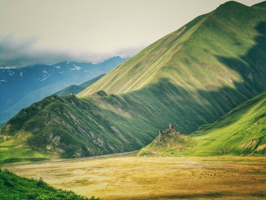 Green mountain under white sky during daytime — Kazbegi, Georgia