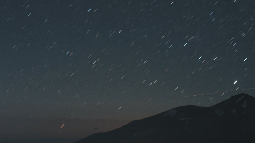 silhouette of mountain under starry night