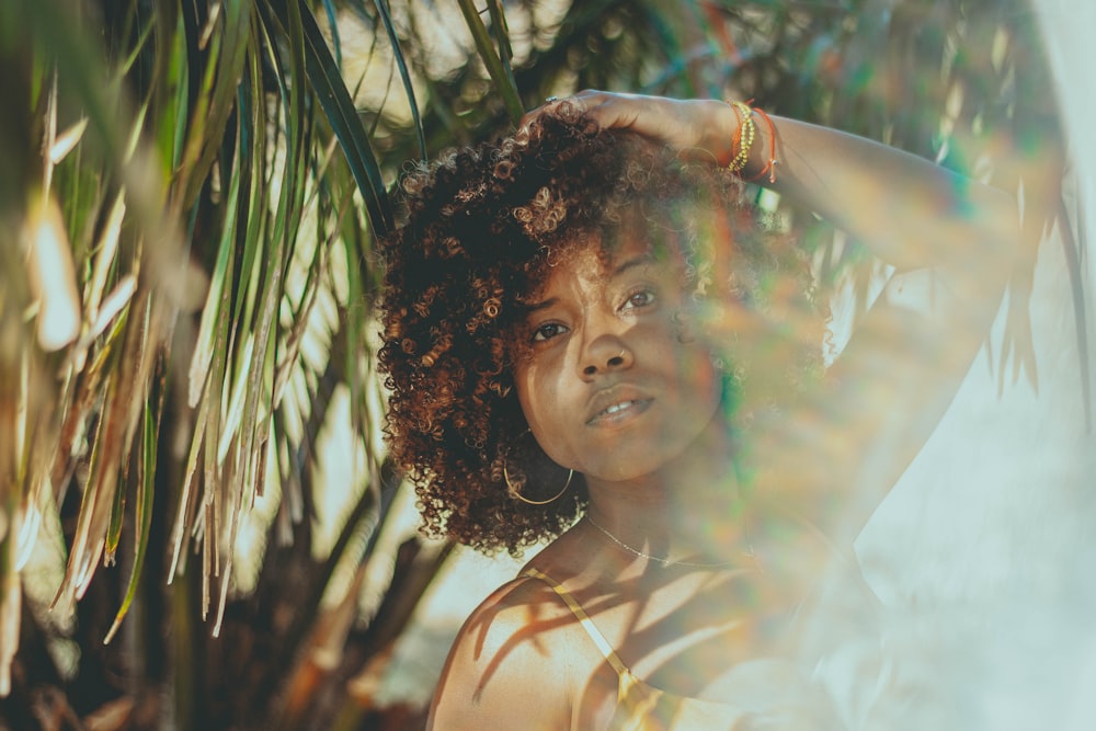 woman in white tank top with brown curly hair