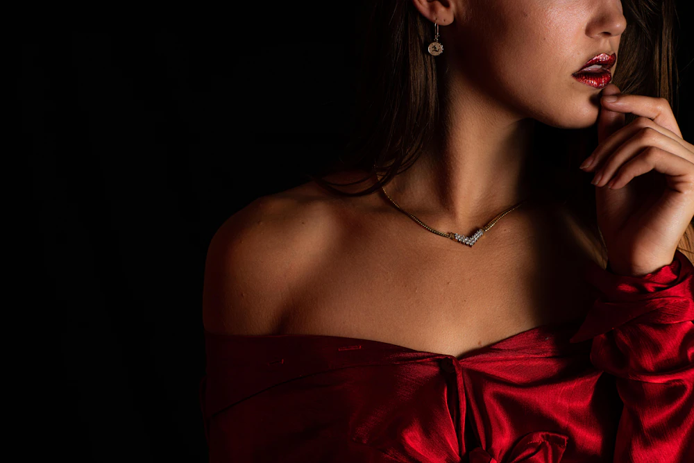 Adult woman in a red satin off-shoulder top wearing a fine diamond necklace and drop earring