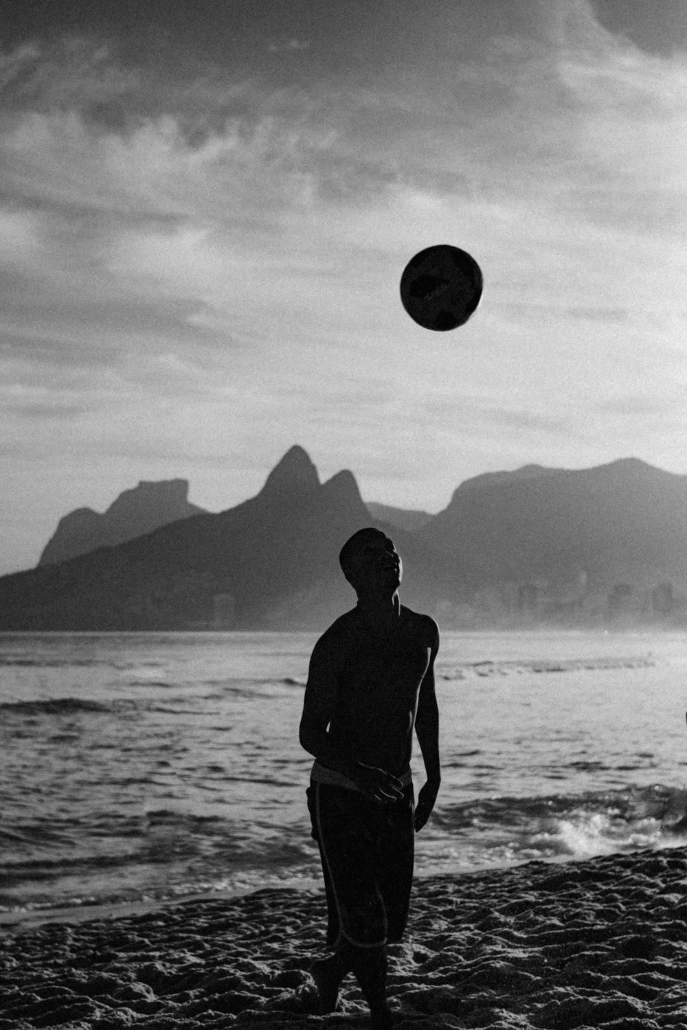 silhouette of man standing on seashore during daytime