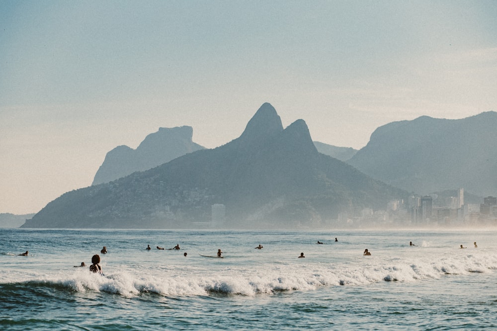 man surfing on sea near mountain during daytime