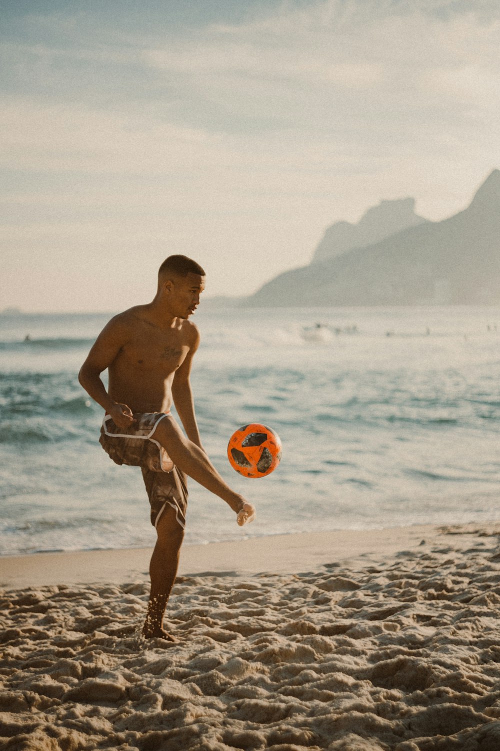 uomo in pantaloncini rossi che tiene palloncini gialli e rossi sulla spiaggia durante il giorno