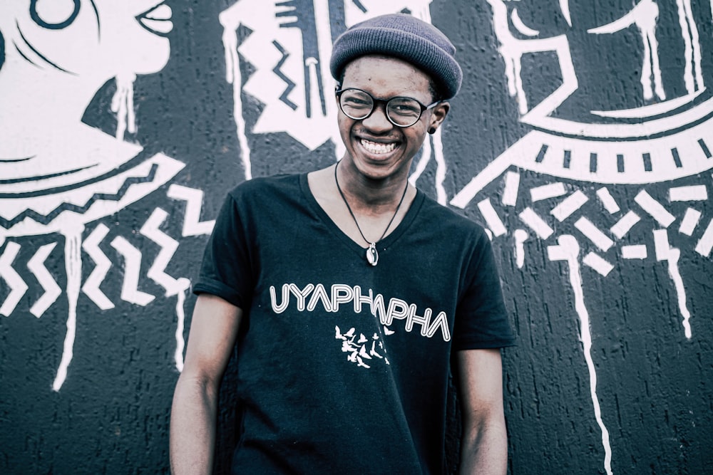 man in blue crew neck t-shirt standing beside wall with graffiti