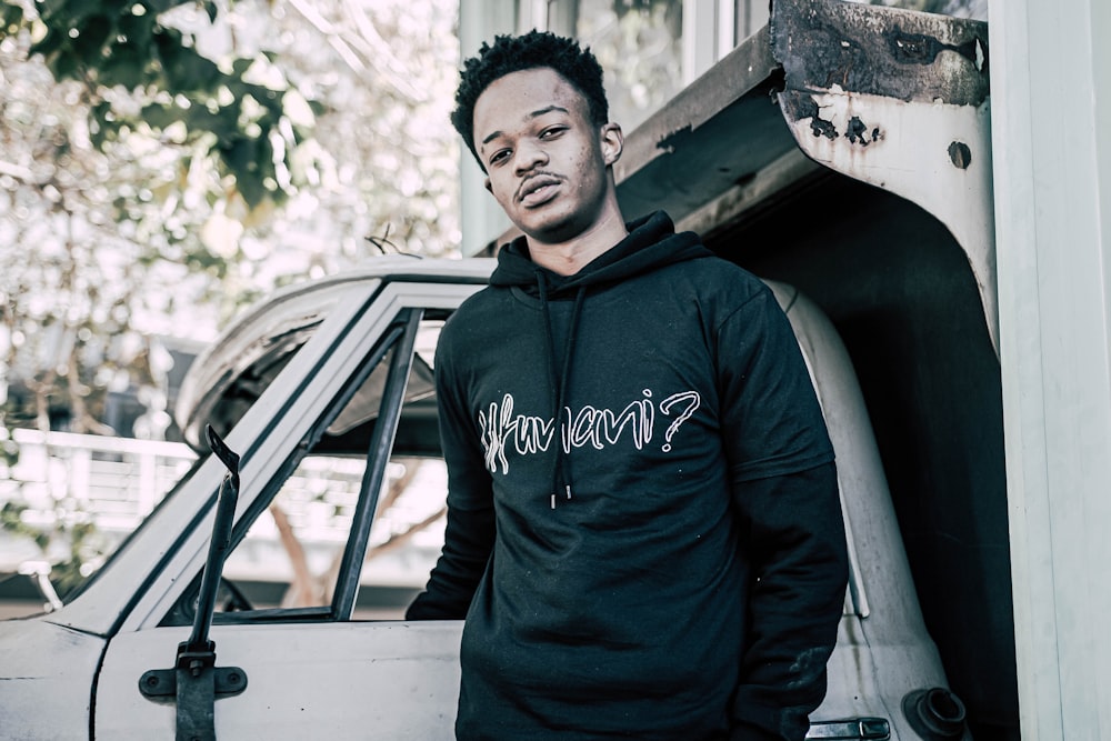 man in blue adidas hoodie standing beside white car during daytime