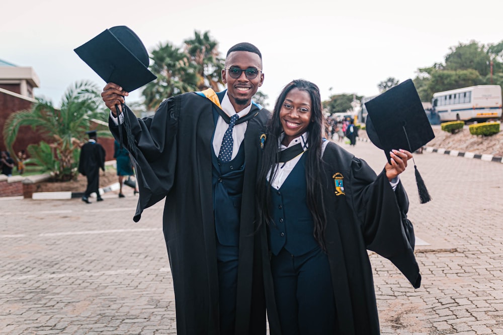 2 men in black academic dress standing on brown concrete floor during daytime